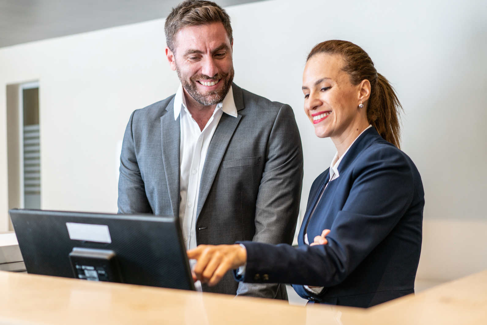 Hotel manager giving instructions to receptionist at front desk of hotel